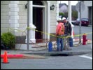 Workers at the northeast corner of Town Hall, the 'Sheriff's Office' door, spray dark 'weathering' paint here and there to give the building that 'been here a long time' look